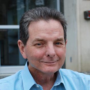 Kevin Sweeney, sitting outdoors on steps.