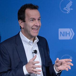 Salzberg stands at podium, smiling as he describes his research.