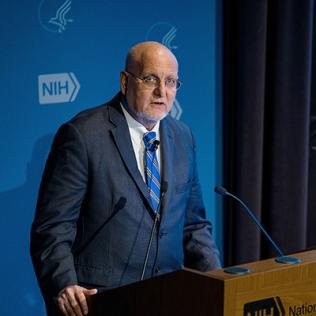 Dr. Robert Redfield is speaking at podium.