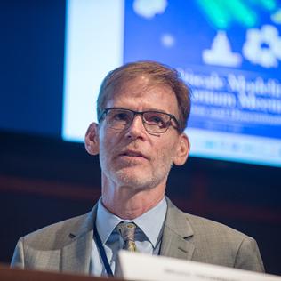 Closeup of Tromberg with slide projected behind him