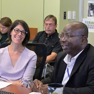 Hull smiles at Adeyemo as he begins his presentation in an NCI conference room.