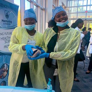 Two young women hold a model of a brain.
