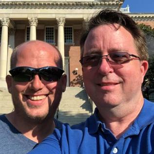 Chris and Jason Plummer smile as they pose in front of Bldg. 1 on NIH's campus.