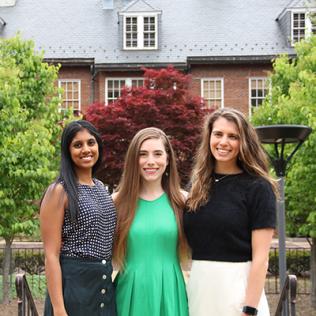 Three yound women smile in front of Lasker Center building