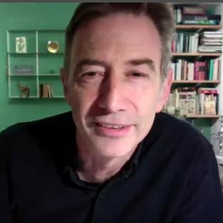 Parker speaks on videocast from his living room, with piano behind him