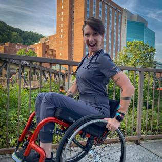 Mason sits in her red wheelchair wearing black scrubs