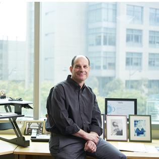 Julius sits on his desk next to his computer 