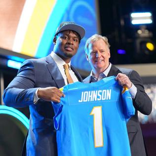 Johnson and NFL commissioner hold up jersey with name on it.