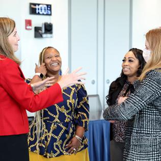 Four women talk informally before start of event.