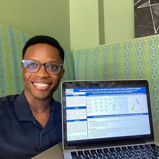 Crump smiles next a laptop. A digital copy of his poster is on the laptop's screen