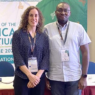 Dr. Bonnie Joubert and Kana stand together in front of their booth, in front of H3Africa backdrop.