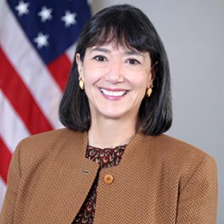Bertagnolli in brown jacket with American flag in background
