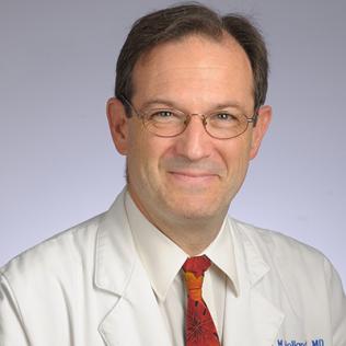 Holland smiling, in white lab coat and tie