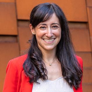 Headshot of Gabriel, smiling, wearing red cardigan