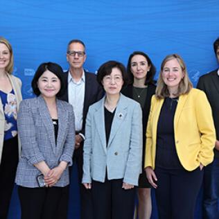 The Korean delegates pose with VRC staff against a blue backdrop bearing the NIH logo.