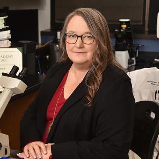 James sits next to a microscope.