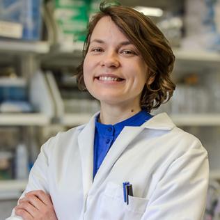 Gribonika smiling in white lab coat in lab