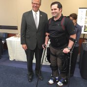 Hultgren with Reese using a robotic exoskeleton to stand