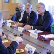 NIH leaders talk with congressional delegation, seated around board room table.