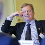 Simpson sits, elbow resting on a chair, listening to research updates.