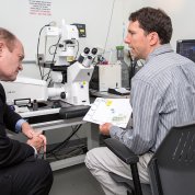 Coons and Burman sit with microscope between them