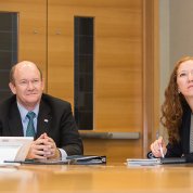 Fauci gestures toward slideshow as he briefs Coons.