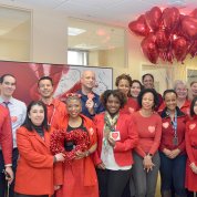 Large group of people wearing red smile for camera.