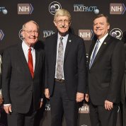 Discovery Channel executives with Dr. Collins, Sen. Alexander and Rep. Cole pose together in front of NIH-Discovery Impact banner in Reagan Building.