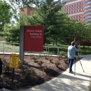 Two photographers stand outside the Clinical Center with their cameras, taking photos.