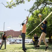 NIH'ers leap up to the net to hit a volleyball outside the Clinical Center.