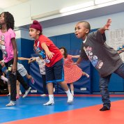 Kids balance on one foot in a classroom in the building 31 gym.