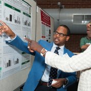 Jones gestures toward his poster as Valantine observes