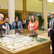 Gilman points at model of Clinical Center in the atrium, with OMB officials and Collins looking on
