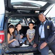 Cpl. Charles Abbington sits in the back of police SUV with youngsters.
