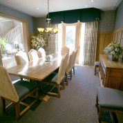 View of room from corner showing large rectangular table, 8 chairs with floor-to-ceiling window in background