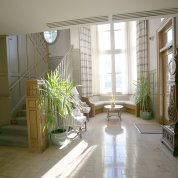 View of nook beside the staircase showing a circular sofa and coffee table with large window behind them