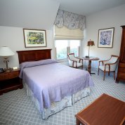 View of room with double bed, nightstand, table and 2 chairs, and wooden wardrobe