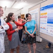 Dr. Steven Holland Dr. Maryland Pao listen to Elizabeth Holland present her poster.