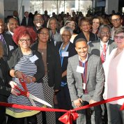 A smiling group of NIH'ers hold big scissors to cut the red ribbon marking the exhibit's opening.