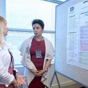 Two women talk in front of a scientific poster at the forum.
