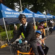 A smiling Dr. Chittiboina on his electric cargo bike with his two young kids in tow