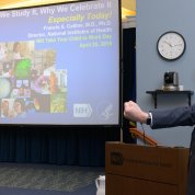 A smiling Dr. Collins with fist extended talks with kids about DNA.