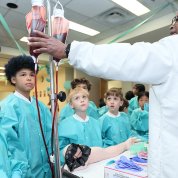 Kids dressed in scrubs look at blood bags at a Fantastic Voyage learning station.