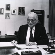 Smiling, Stetten sits at his desk.