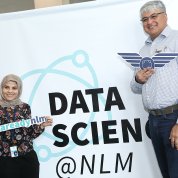 Two attendees stand in front of a sign that reads "Data Science @ NLM"