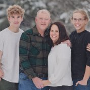 A wintertime photo of the Schmaedeke family, posing outside, surrounded by snow flurries