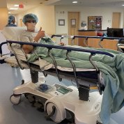 Luke gives thumbs up on hospital bed in hallway of the Clinical Center.