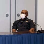 A police officer in a face mask seated at conference table