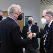 Van Hollen shakes hands with Tabak, as Trone and Cardin look on. All are wearing masks.