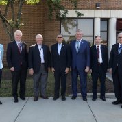 Outside, group of people standing side by side, smile into camera